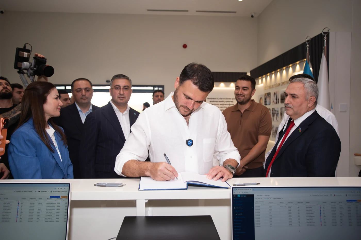 Uzun piştaxtalı və şüşə şkaflı otaq; sənədin imzalanması gedir